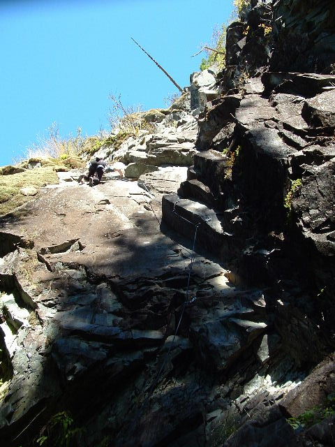 a man walking up a steep rocky cliff