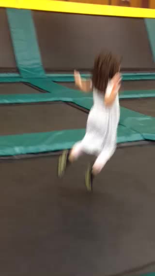 a little girl is running on a trampoline at a fun center