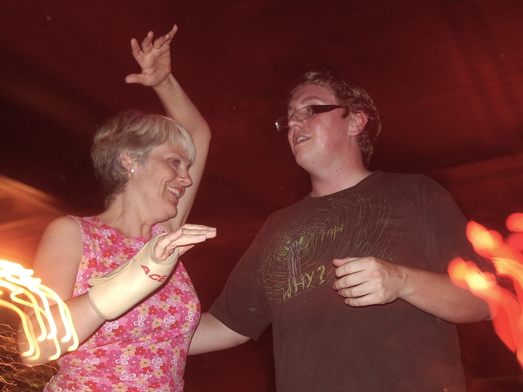 an old man and young woman are dancing with lights in the background