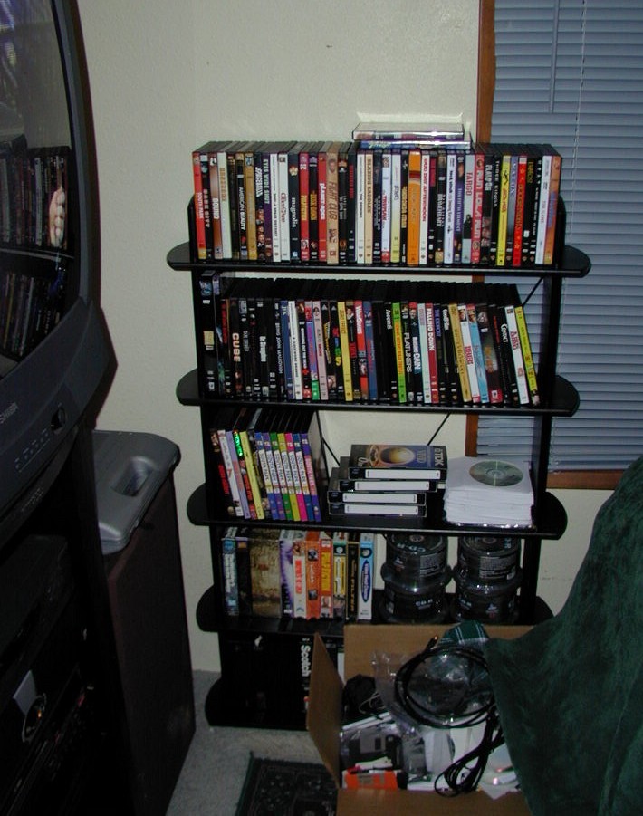 a tv is sitting behind some shelves full of dvds