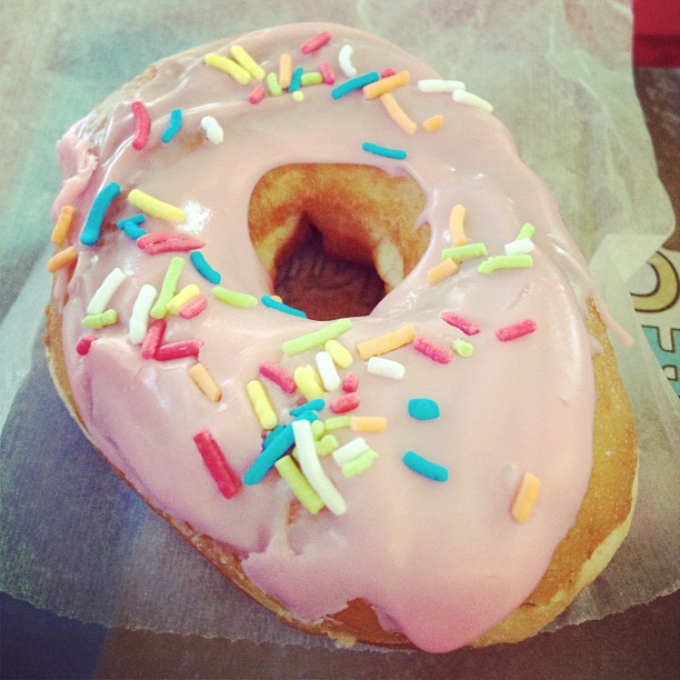 a frosted donut with pink glaze and sprinkles