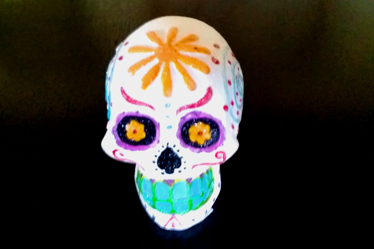 an artisticly decorated sugar skull against a black background