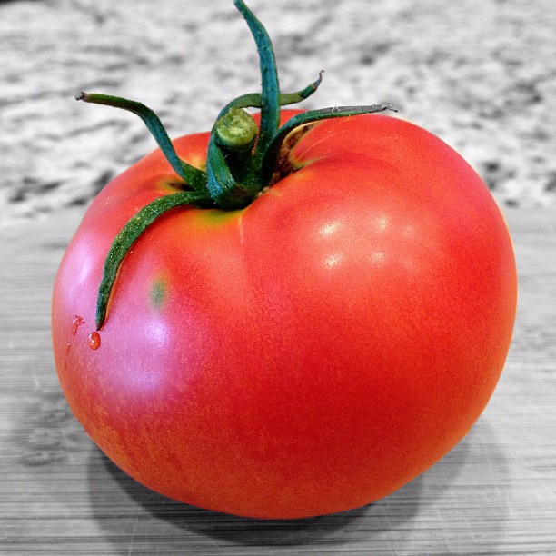 a large red tomato is sitting on a wooden table