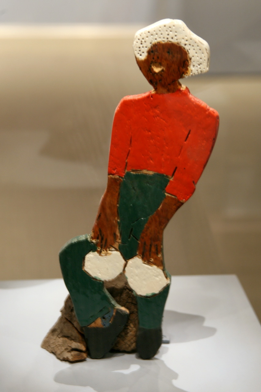 a wooden figure with a hat sitting on a piece of paper