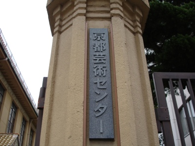 a tall building with japanese writing and a black gate