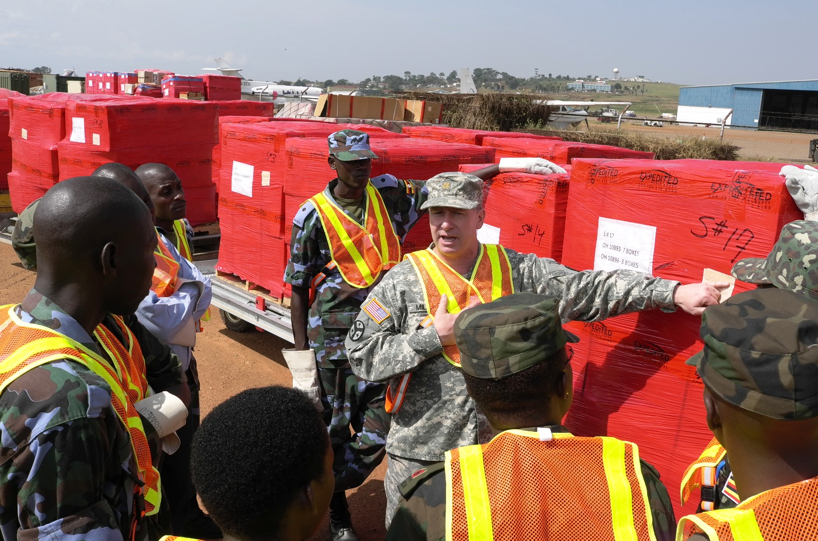 a man standing next to many red crates on top of a field