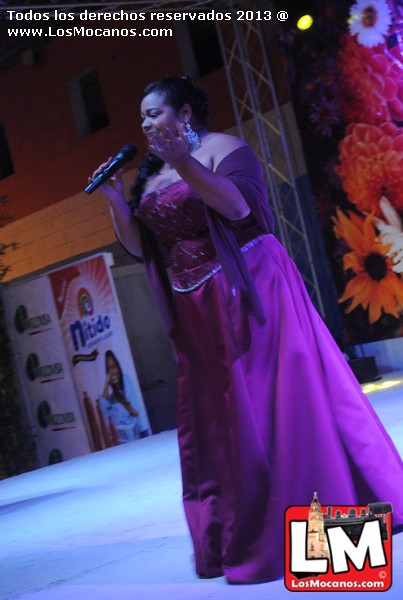 a woman in purple dress with microphone on stage