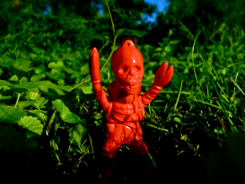 a toy figure sitting in the middle of a lush green field
