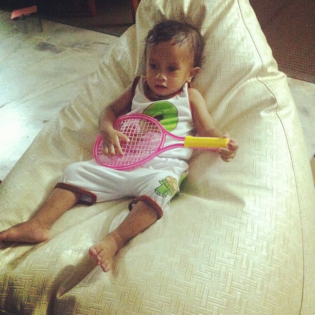 a baby on a couch holding a tennis racket