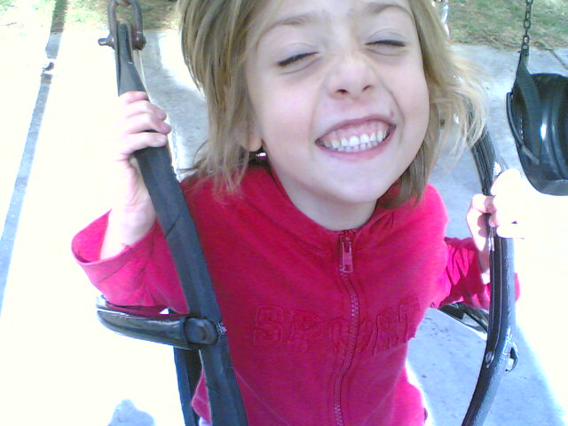 a little girl with her mouth open on a swing