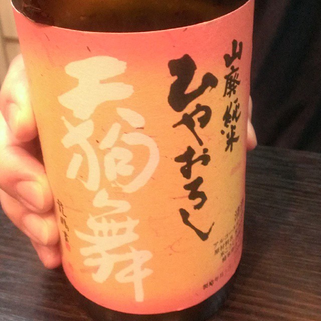 a person holds up a beer cup with an asian writing