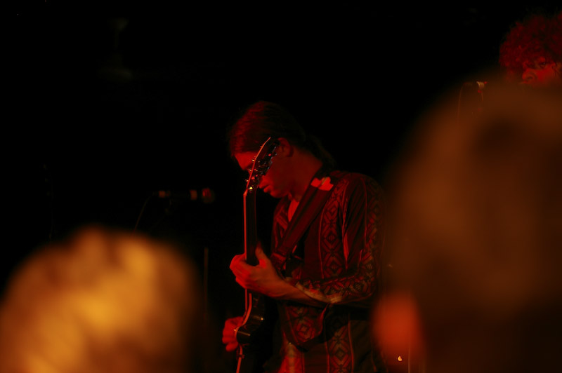 an musician plays a guitar while standing in a crowded place