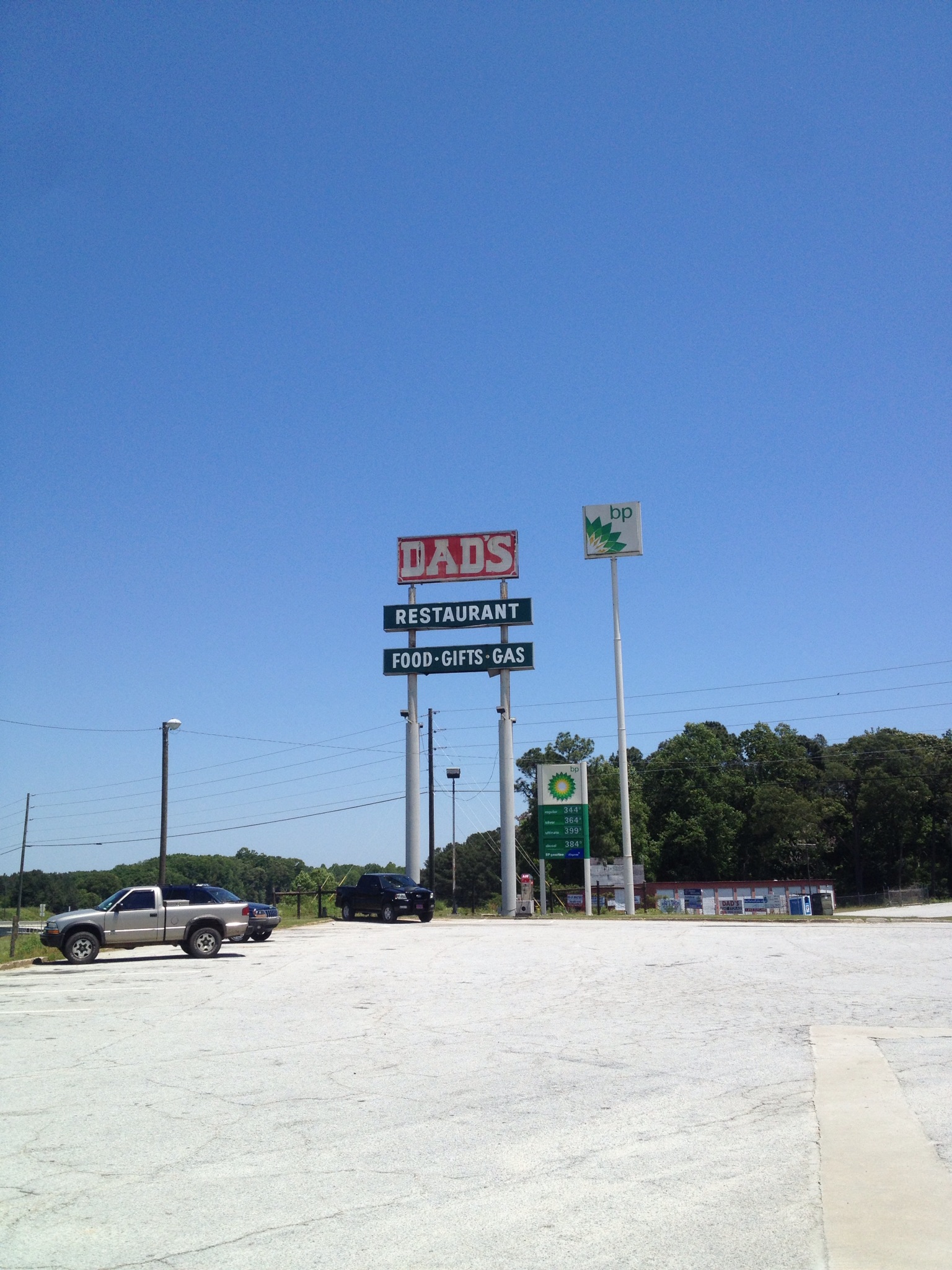 a group of three signs for a gas station and a parking lot