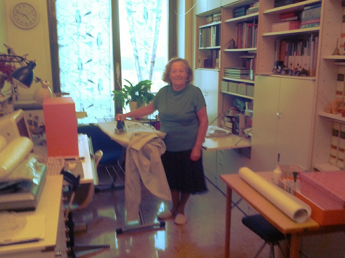 an elderly woman is sewing while she looks over her shoulder