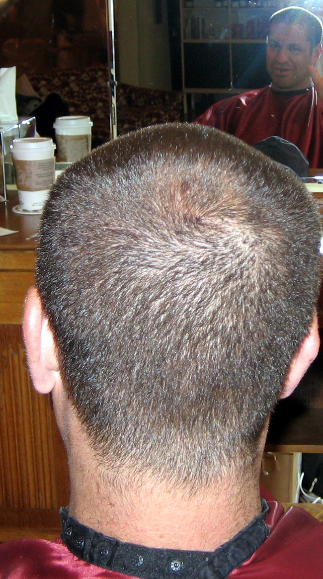 a man sitting in front of a mirror with his hair cut