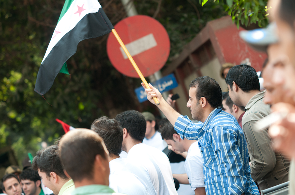 many people and one guy holding an olive shaker and a flag