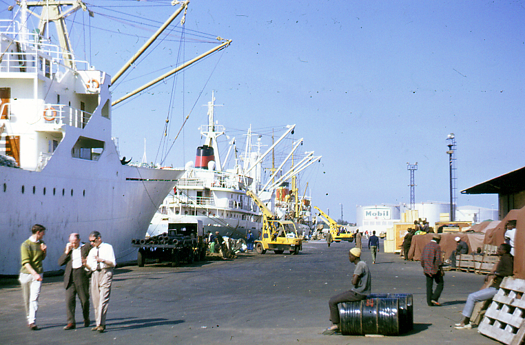 several people standing in front of many large ships