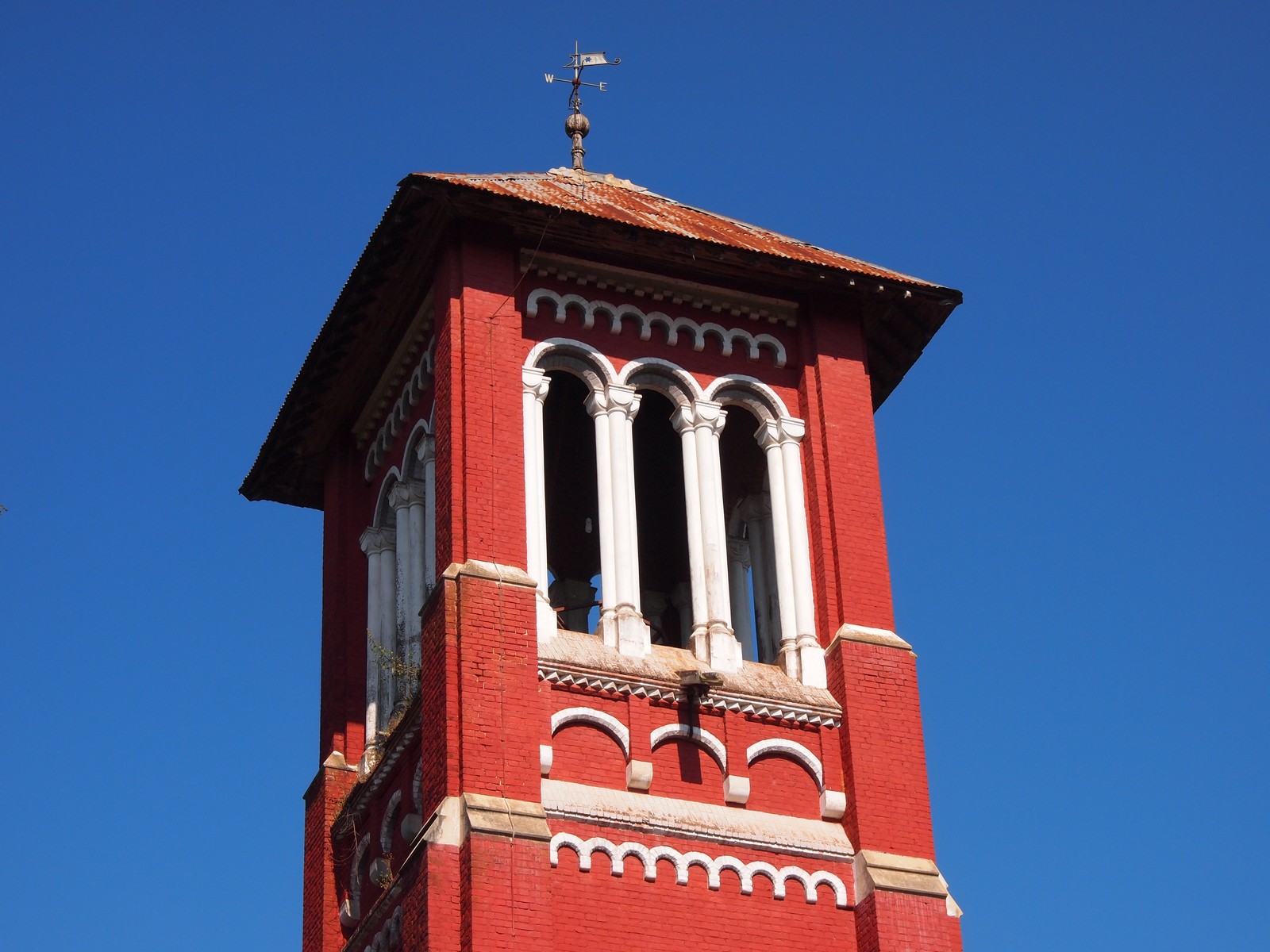 an old fashioned red clock tower is seen against a clear blue sky