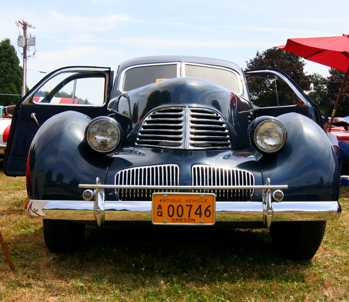 the front end of an old blue and black classic car at a car show