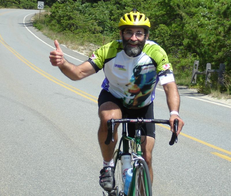 man in a helmet riding a bicycle gives thumbs up