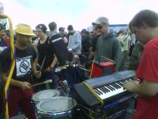 a man playing on a keyboard while others look on
