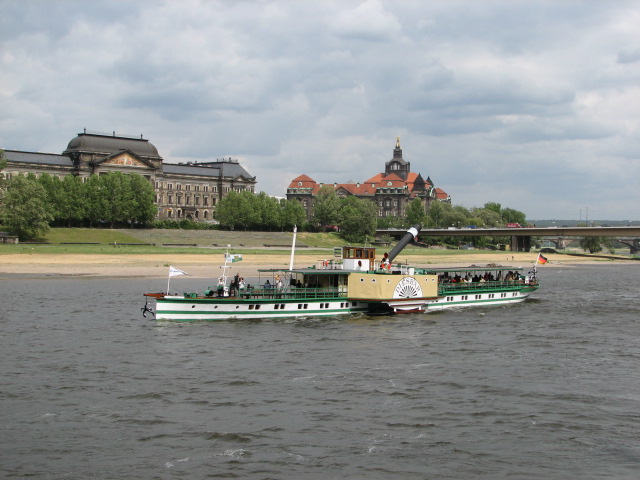 a boat traveling down the river with large buildings in the background
