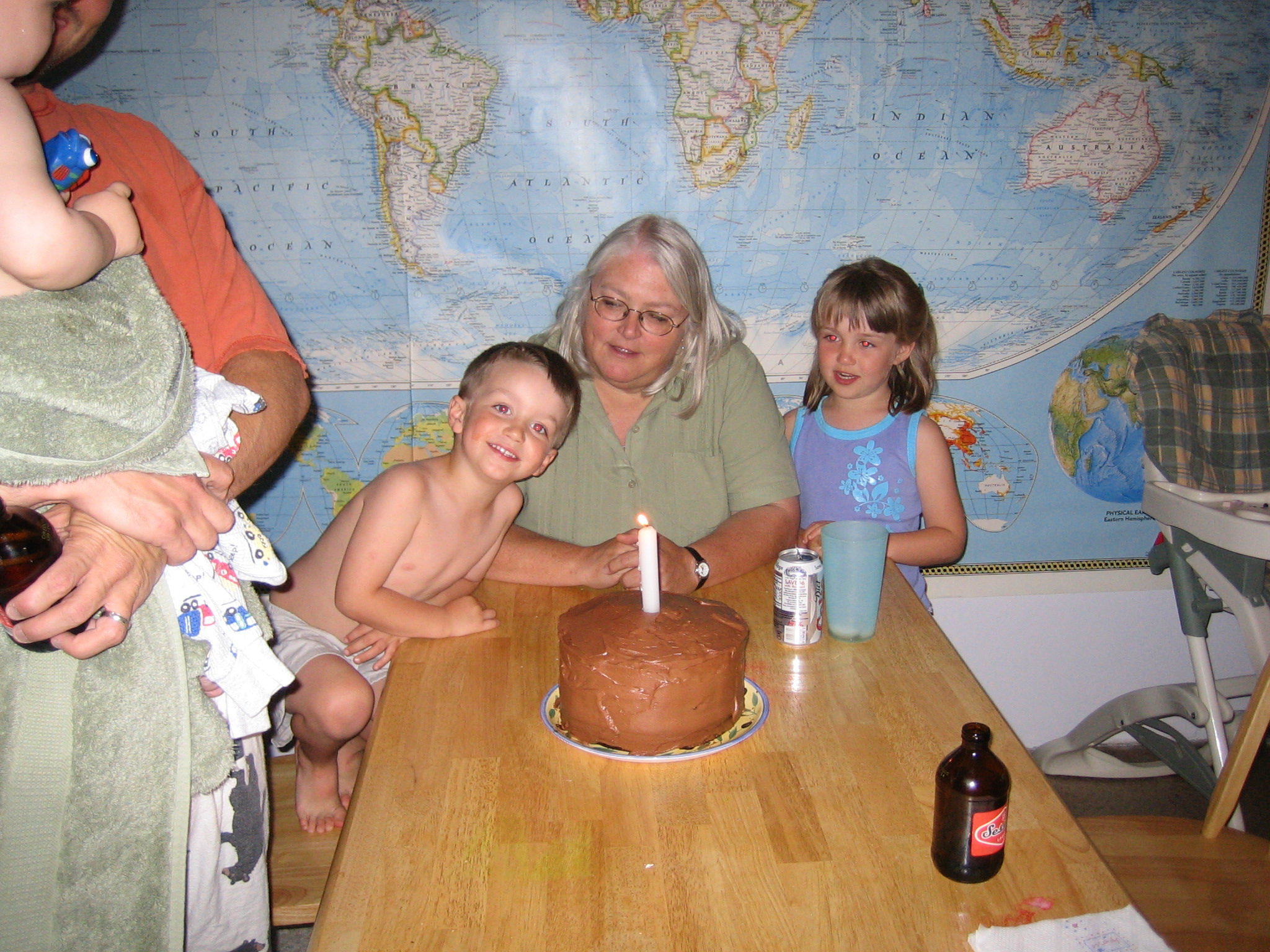 a family poses around a chocolate cake with candles in it