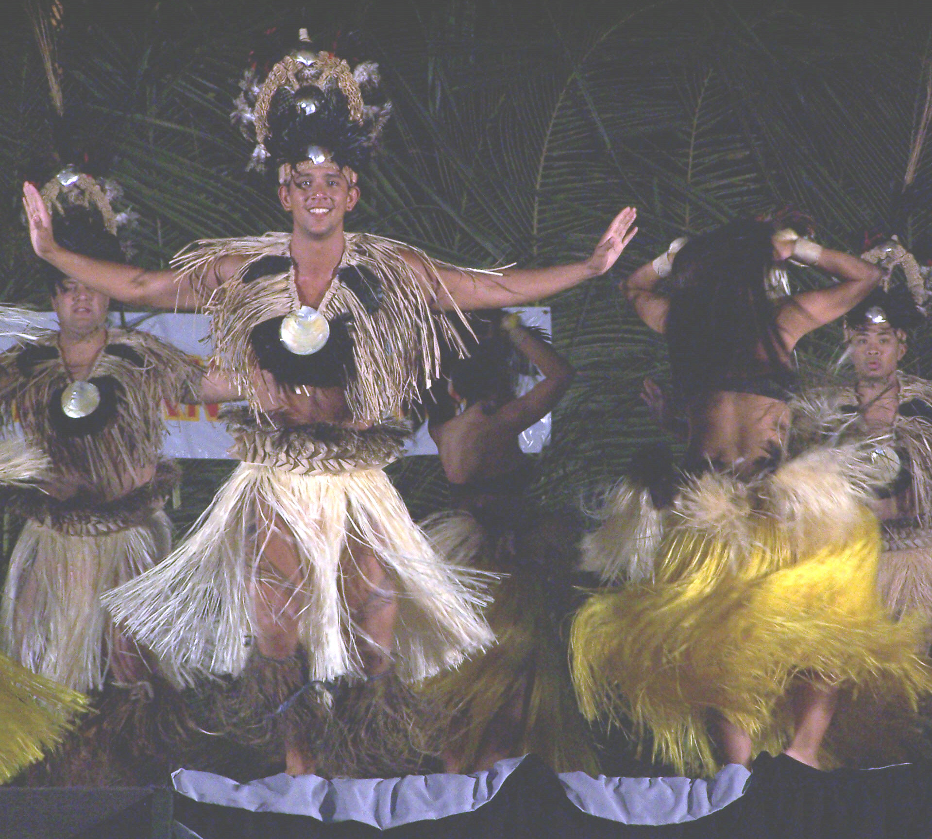 woman wearing an ornate hula skirt in front of some other people