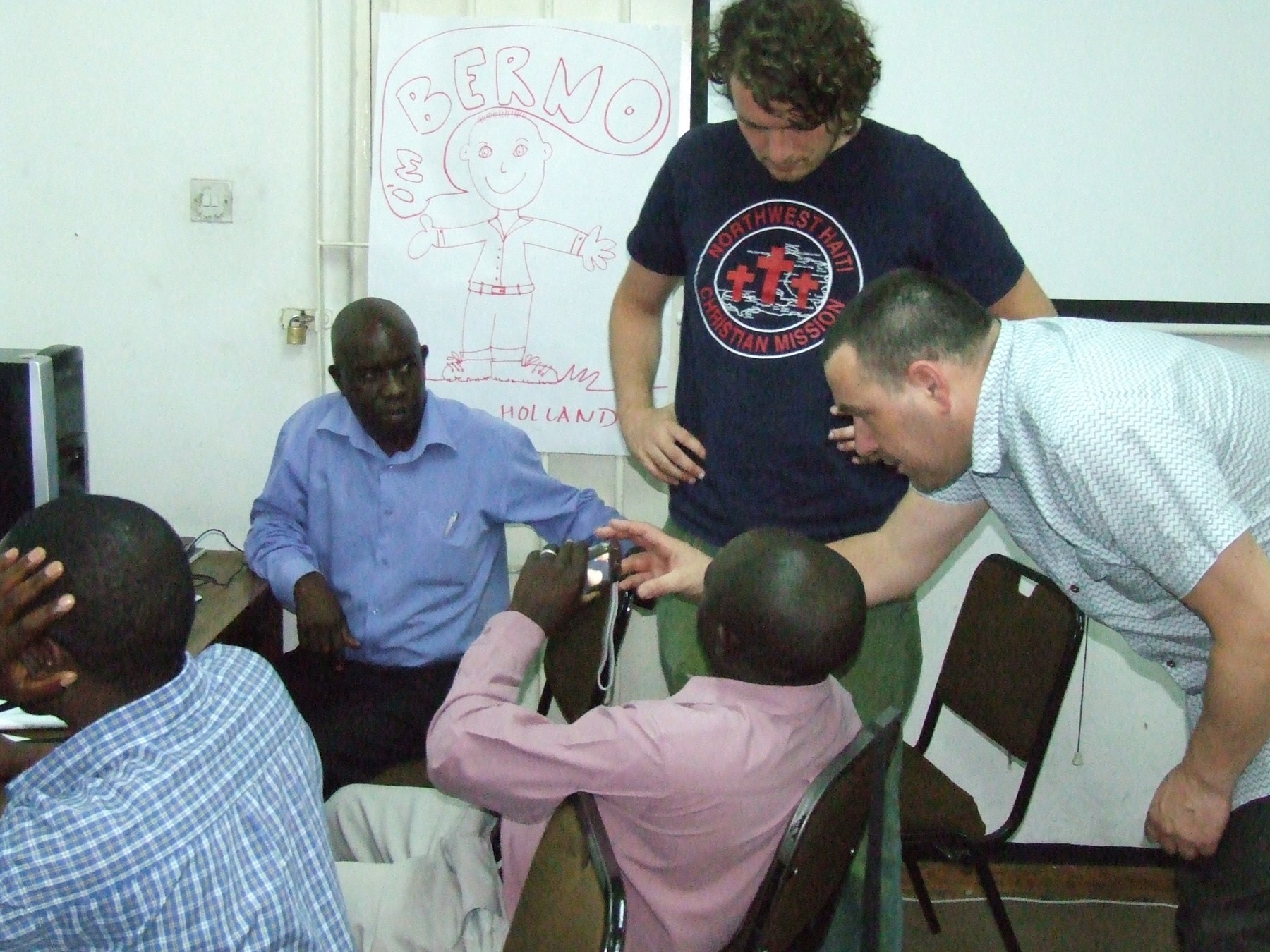 a group of men gather around a table with remotes