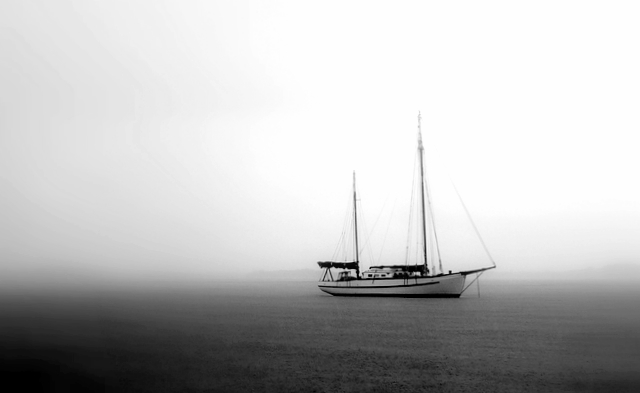 a small sailboat on the water in black and white