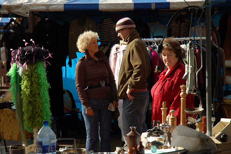 people looking at a flea market with umbrellas on the tables