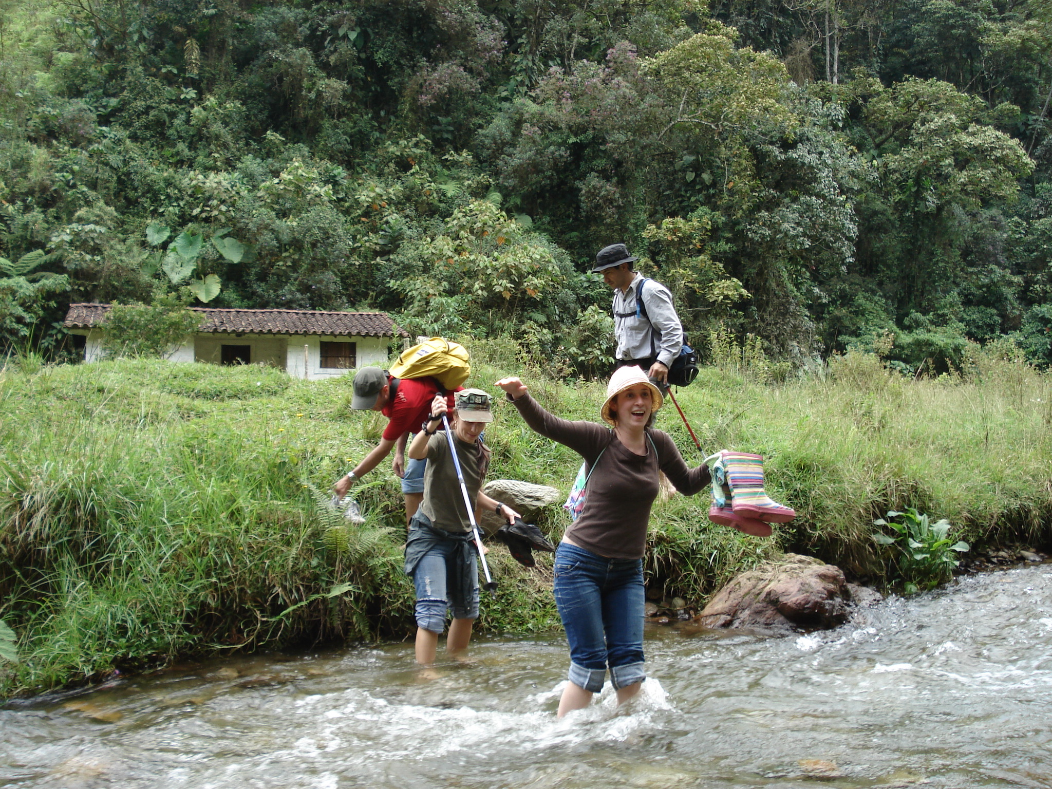 two people crossing a stream in the woods