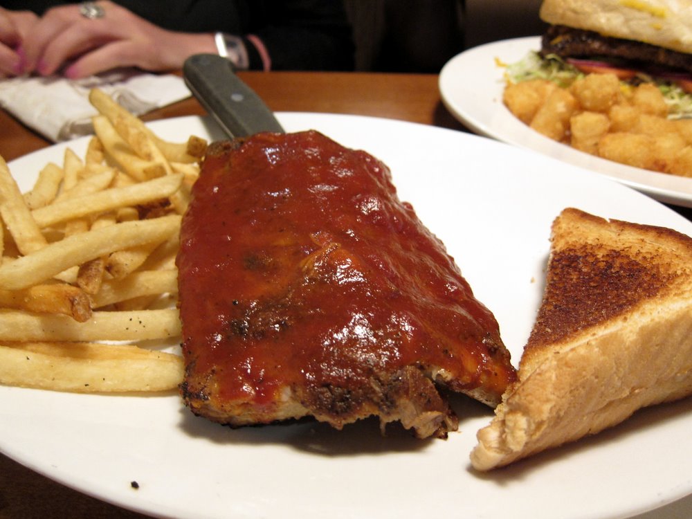 plate with ribs, sandwich and french fries on a table