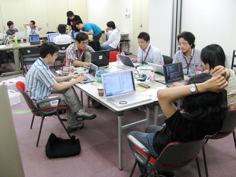 several people sitting in chairs around tables with laptop computers