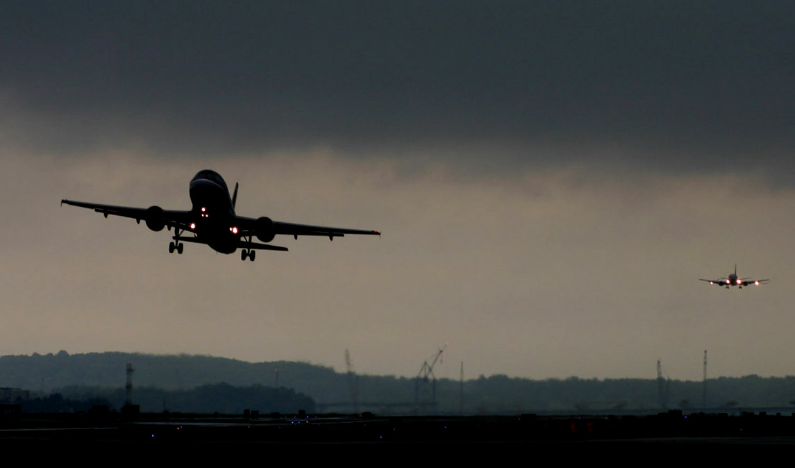 two airplanes are flying in opposite directions with some clouds in the sky