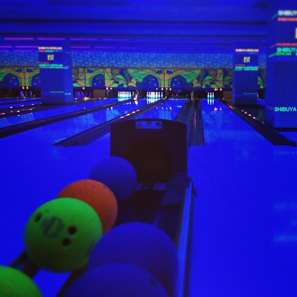 a bowling alley with many neon balls lined up on the lanes