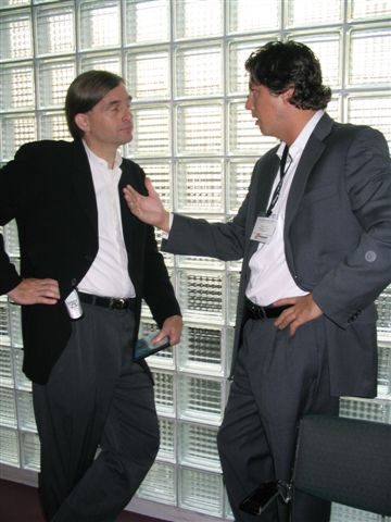 two men talk at a business meeting in front of a backdrop