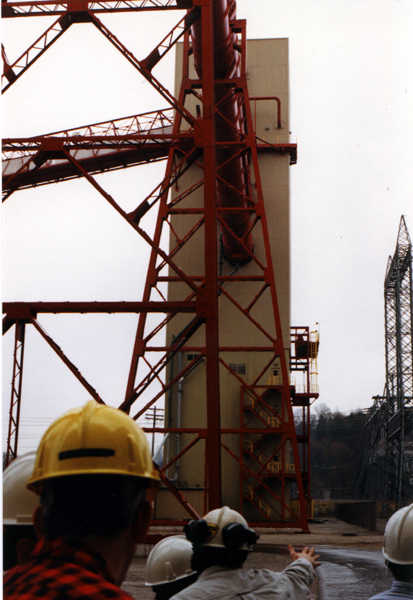 two people wearing helmets and safety jackets watch as a rocket is lifting off