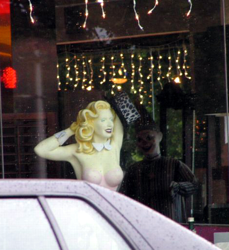 the window of a fashion store with a blonde statue
