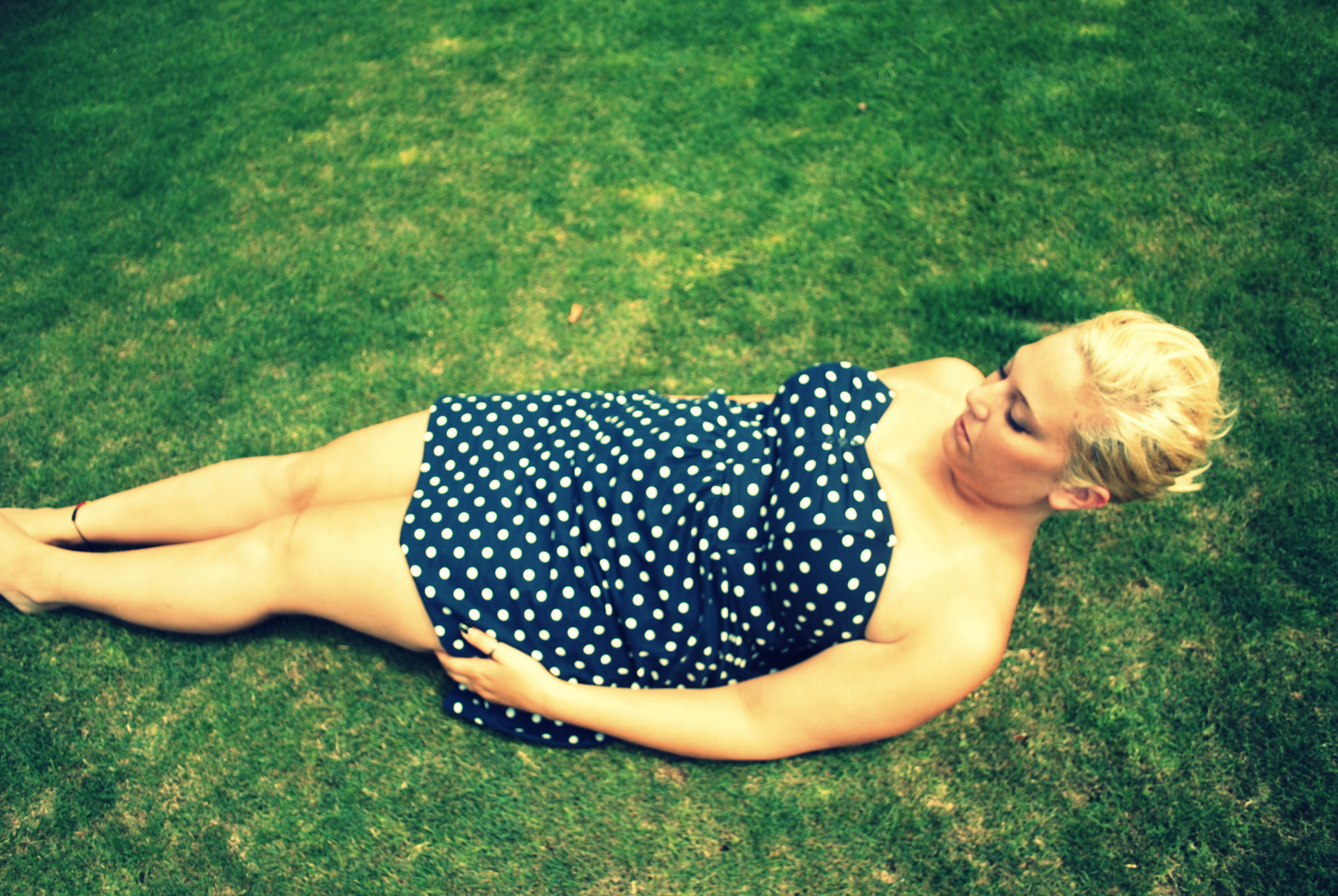 a young woman in a polka dotted dress laying down