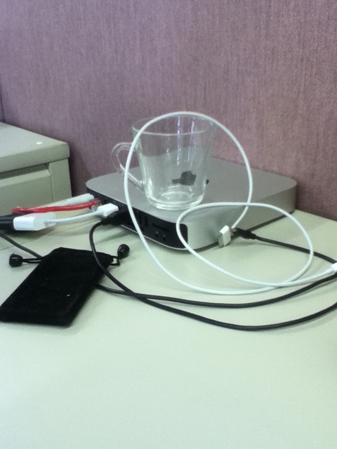 a desk that has a glass and ipod charger on it