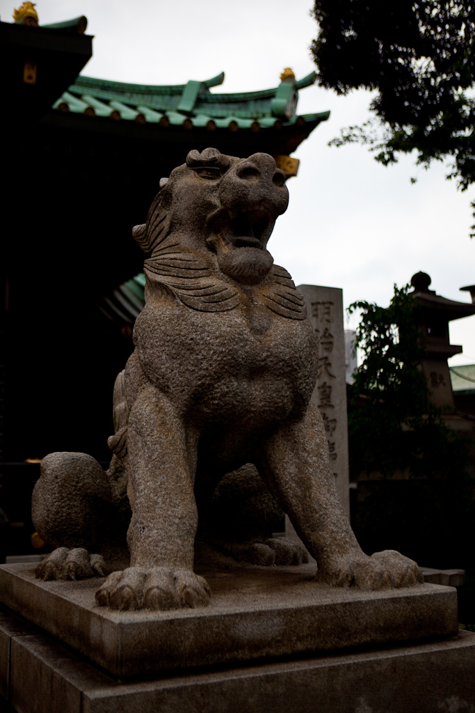 a statue of an asian lion sits on a pedestal