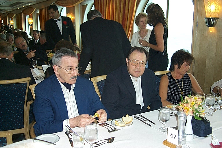 several people sitting at a table with white tablecloths