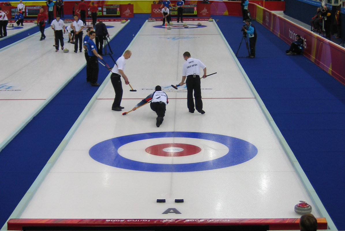 a curling event with men standing on the curling surface