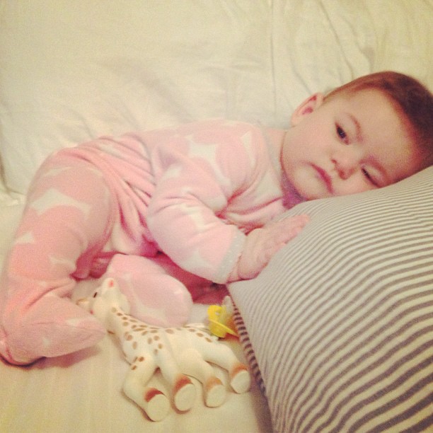 a small child laying next to a pillow with a stuffed giraffe