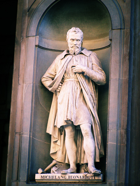 a statue of a man wearing a cloak in front of a building