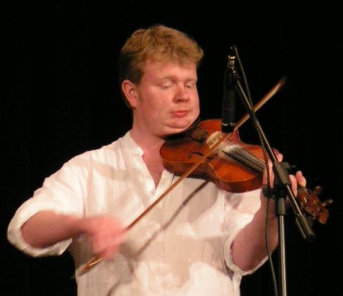 a young man with white shirt and tie playing violin