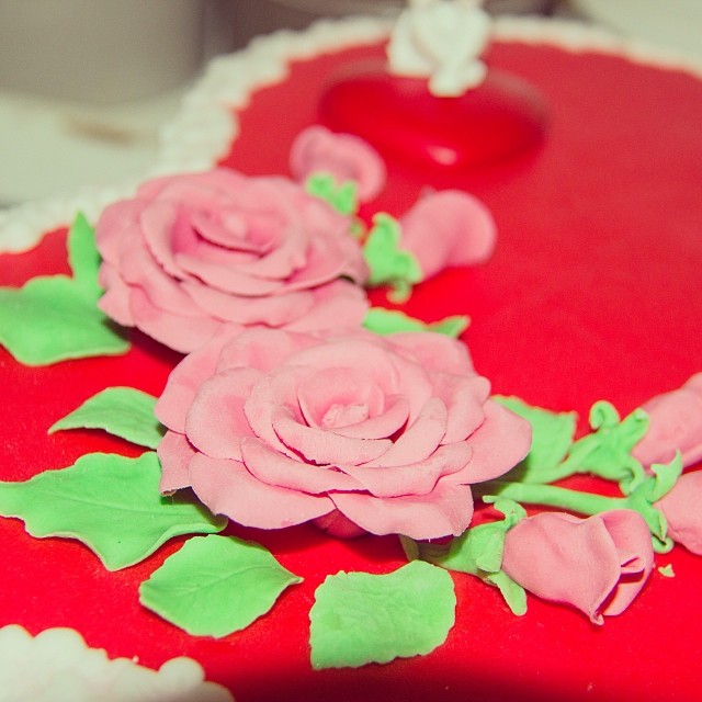 a red round cake with icing roses on it