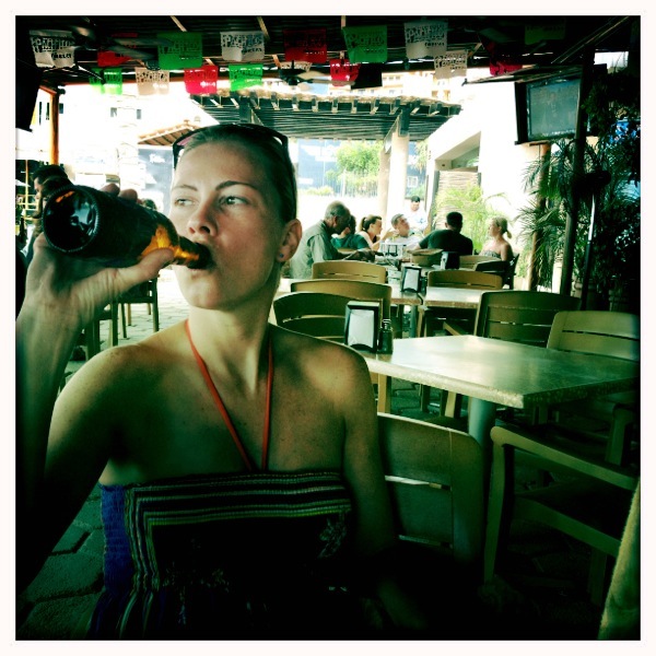 a woman drinking beer from a plastic bottle
