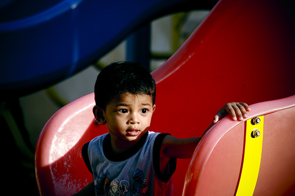 a young child leaning on a large red playground structure